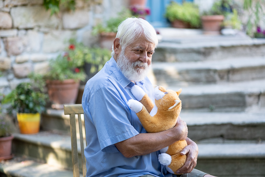 Ein älterer Herr spielt mit der Therapiekatze Smart Cat von RobiCare.
